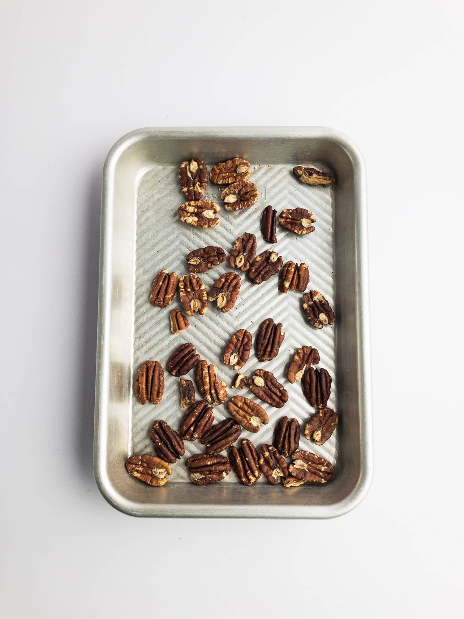 Top-down view of toasted pecans on a baking sheet
