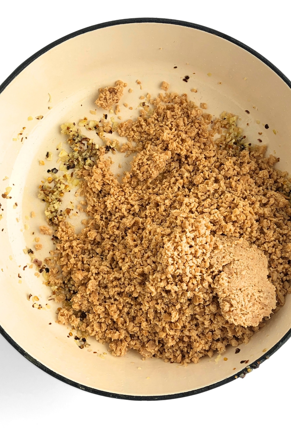 Top-down view of fried spices and TVP added to frying pan.