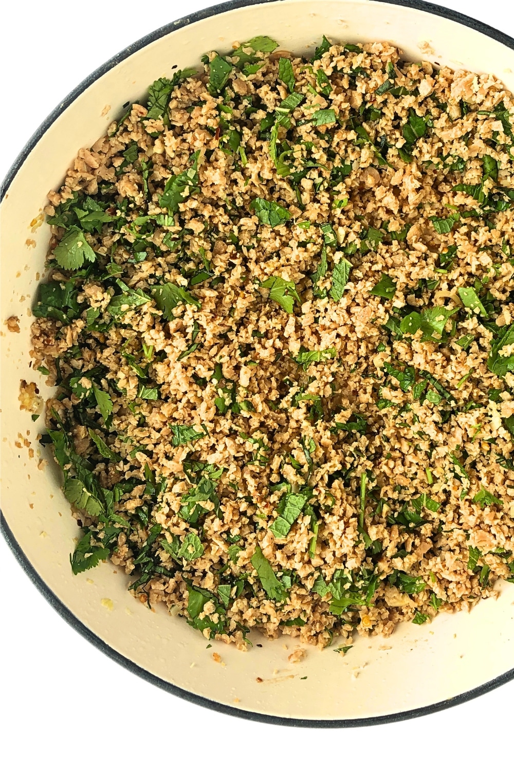 Top-down view of finished vegan larb in a white frying pan.