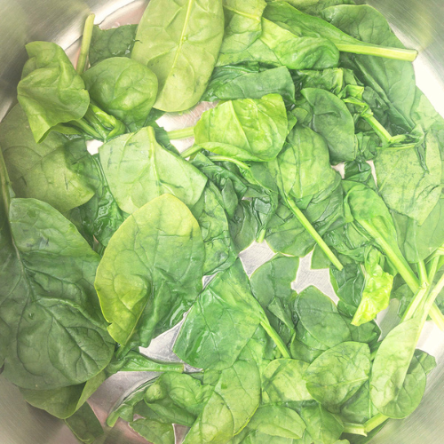 Top-down view of wilted spinach in a frying pan